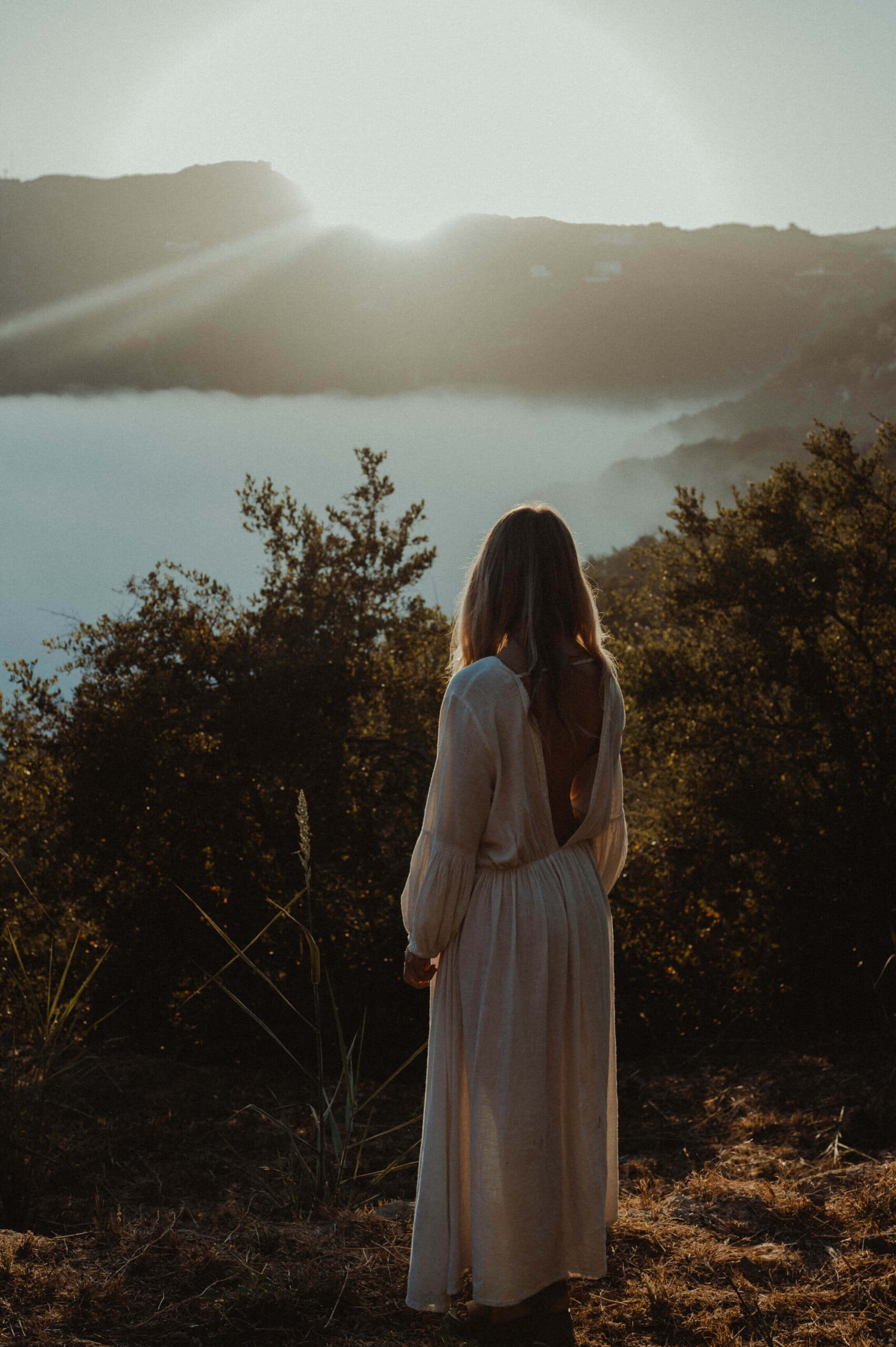Woman looking out over a lake in soft morning light, finding herself again in midlife