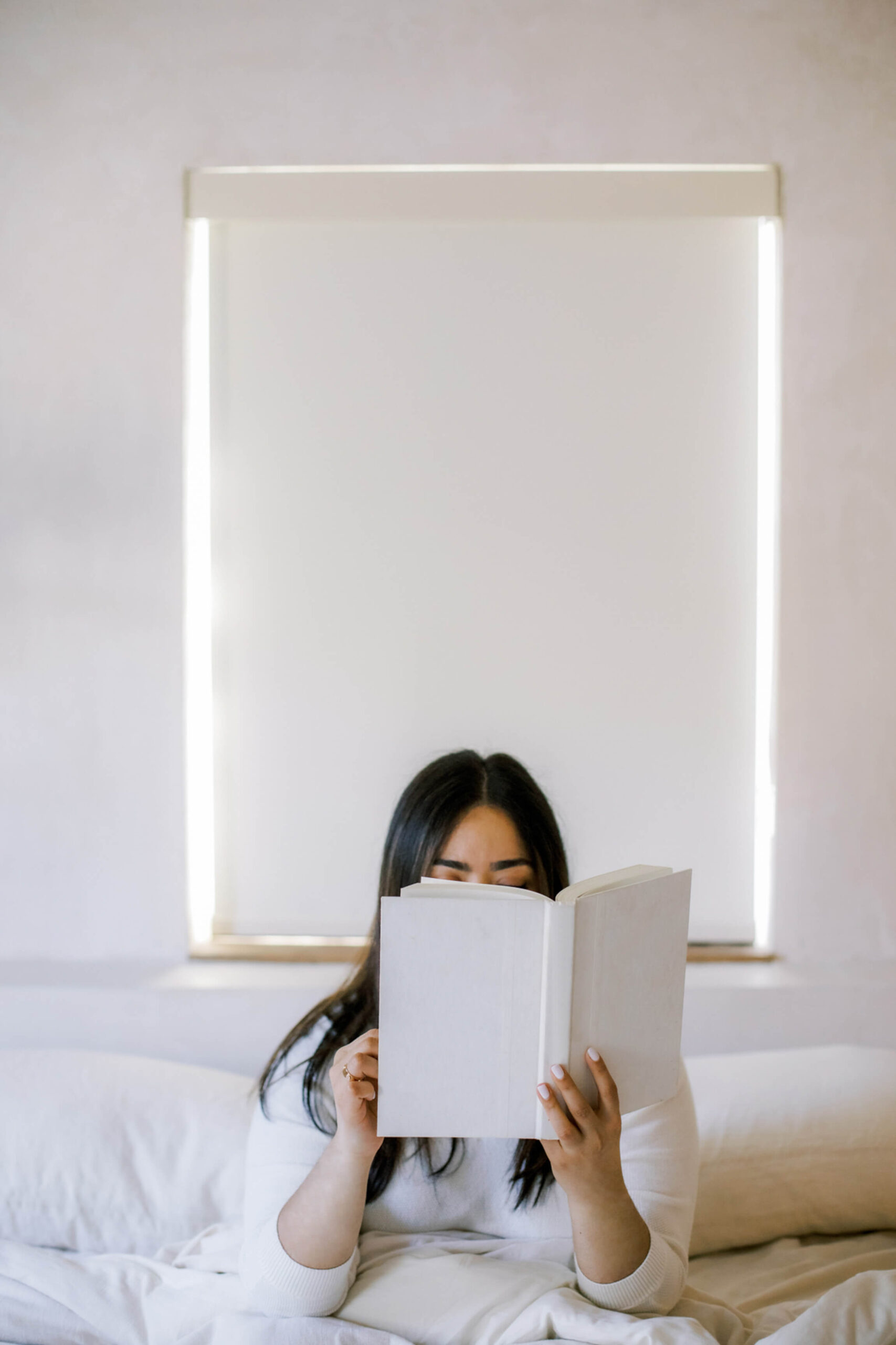 Woman reading in bed, taking a quiet moment before she starts comparing herself to others