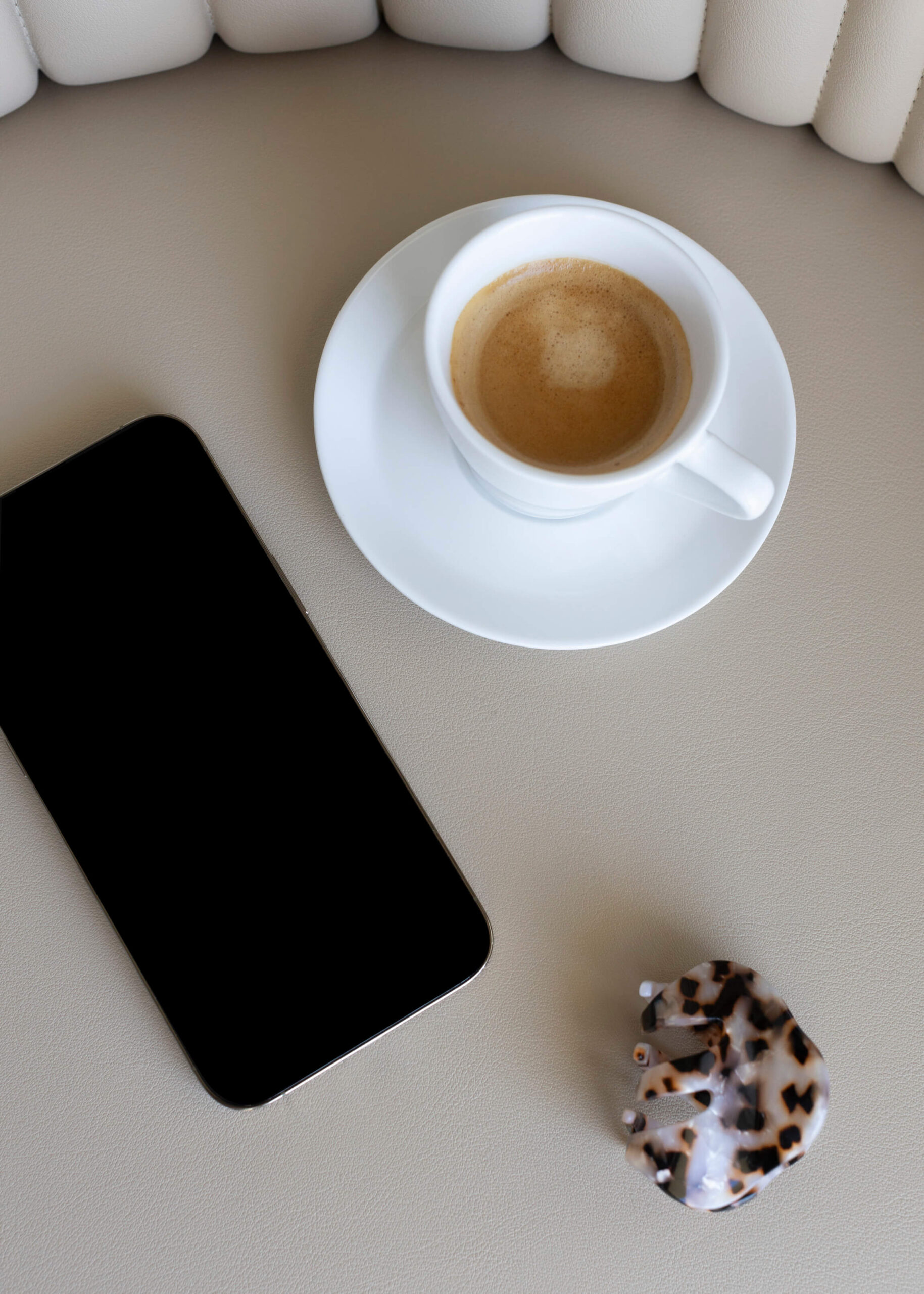 Coffee cup and smartphone on a table, representing the challenge many high-achieving women face when trying to slow down and relax.